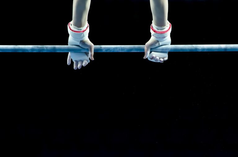 Manos de un atleta agarrando una barra de dominadas